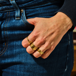 Load image into Gallery viewer, Hand wearing gold rings on blue denim jeans
