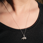 Load image into Gallery viewer, A close-up of a person's neck and chest wearing a delicate silver chain necklace with a small silver animal pendant, paired with a black ribbed top.
